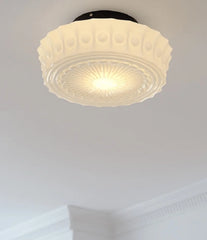 Ceiling light fixture with decorative glass shade on a plain ceiling