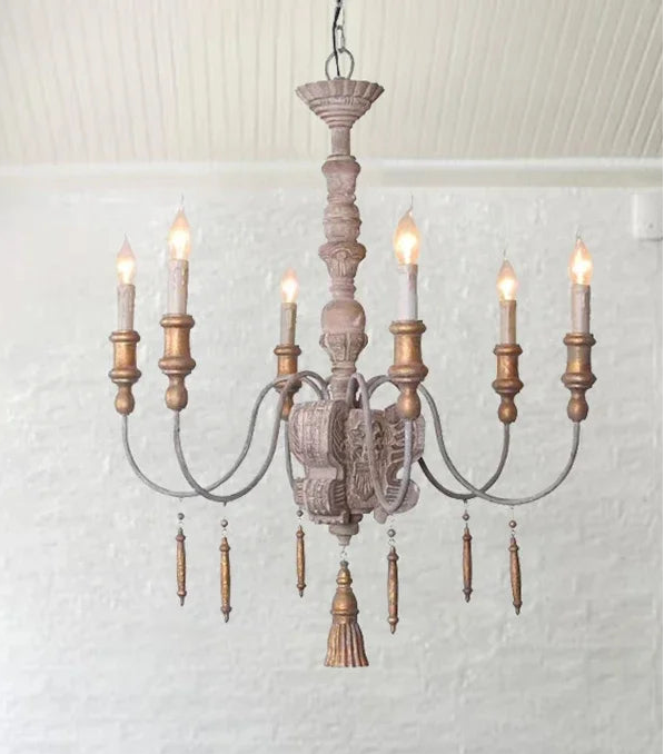 Wooden chandelier with multiple lights in a room with a striped sofa and kitchen area.