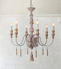 Wooden chandelier with multiple lights in a room with a striped sofa and kitchen area.