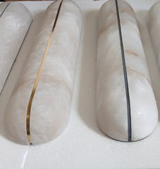 Marble-patterned cylindrical objects with gold and black accents on a white surface.