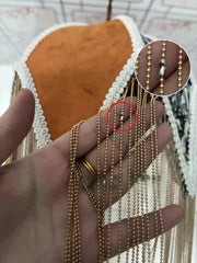 Gold chain on a hand with a close-up inset showing a defect.