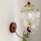 Decorative wall light fixture with crystal accents and butterfly designs on a plain background