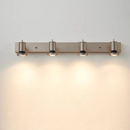 Four adjustable LED wall sconces mounted on a silver bar against a white wall, casting a warm glow downwards.