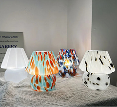 Four colorful glass lamps on a textured surface with a neutral background