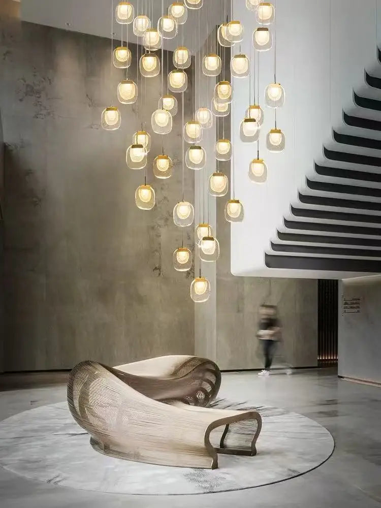 Modern chandelier hanging in a stylish interior with a staircase and decorative chair.
