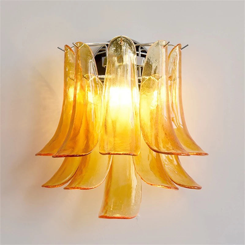 Amber glass petal wall sconce with a chrome finish illuminated against a white wall.