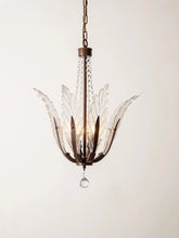 A close-up view of a bronze chandelier with clear glass leaf-shaped shades and a single hanging crystal.