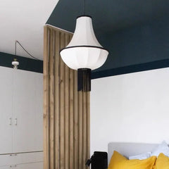 Modern pendant light hanging in a room with a white ceiling and wooden pillar.