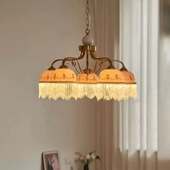 Gold floral ceramic pendant light illuminated, casting a warm glow with white tassels.