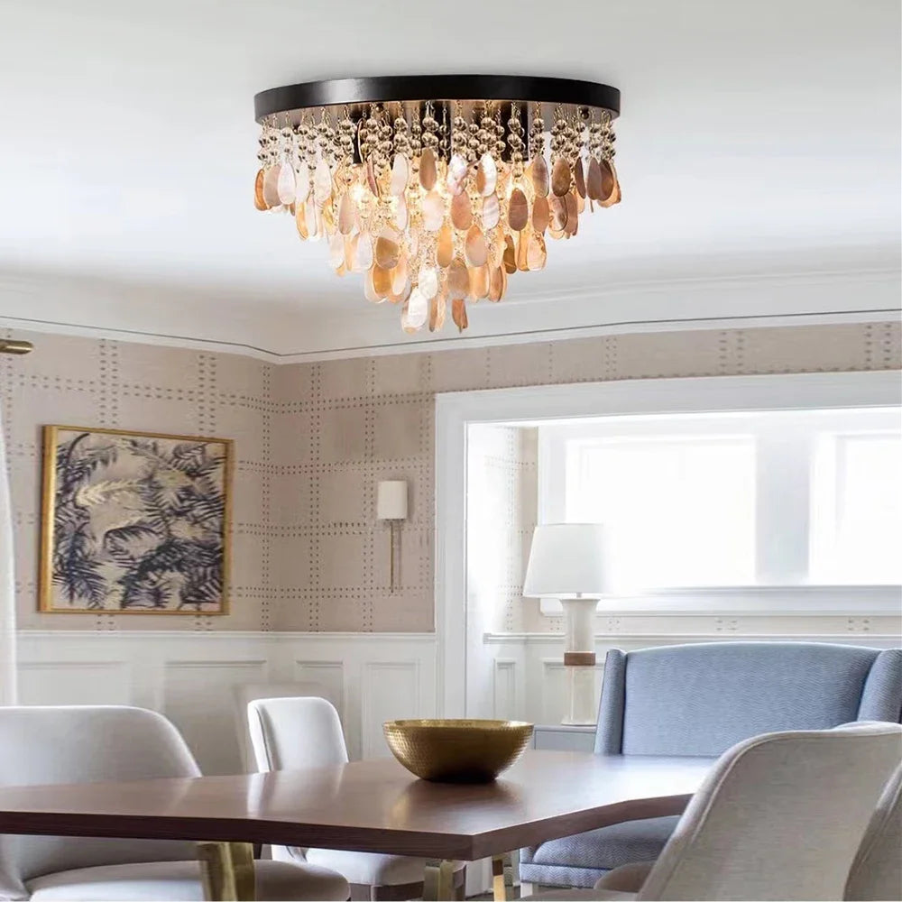 A gold and shell semi-flush mount ceiling light with multiple tiers of teardrop shapes hanging from a circular base, illuminating a dining area.