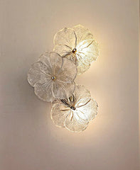 Decorative wall light fixture with floral design on a plain wall.