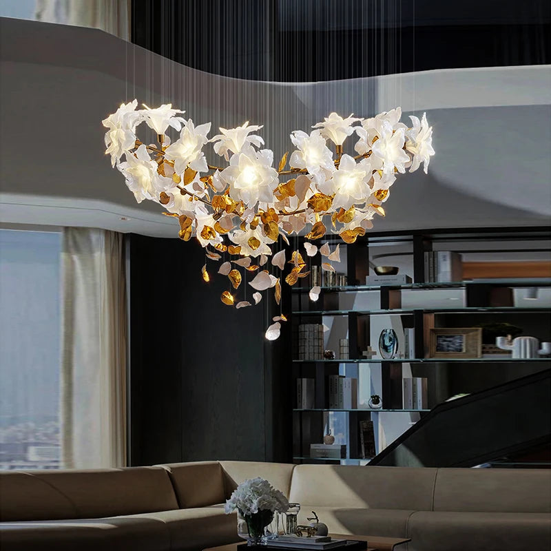 A chandelier shaped like a heart made of gold floral elements and clear crystals, suspended above a living room seating area.