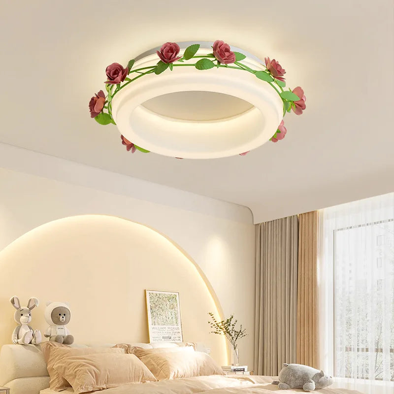 A bedroom with a bed and plush toys, illuminated by a white semi-flush ceiling light decorated with a floral rose vine.