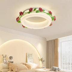 A bedroom with a bed and plush toys, illuminated by a white semi-flush ceiling light decorated with a floral rose vine.