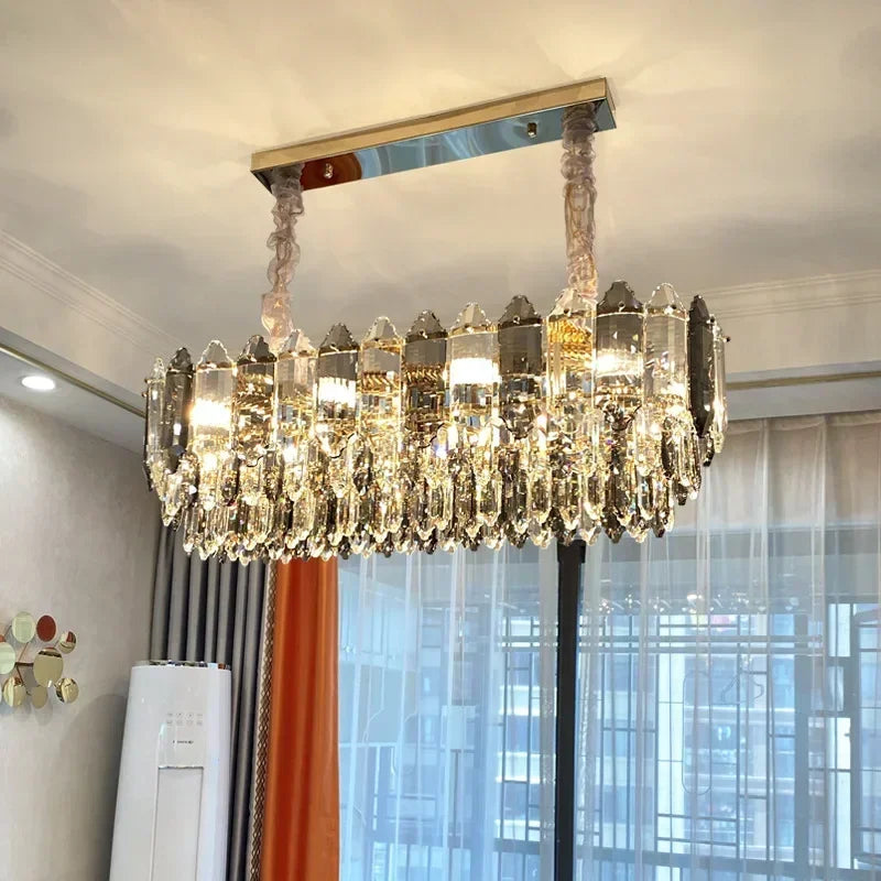 Close-up view of the gold-toned metal frame and crystal droplets of a modern chandelier, showing the faceted design and reflective surfaces.