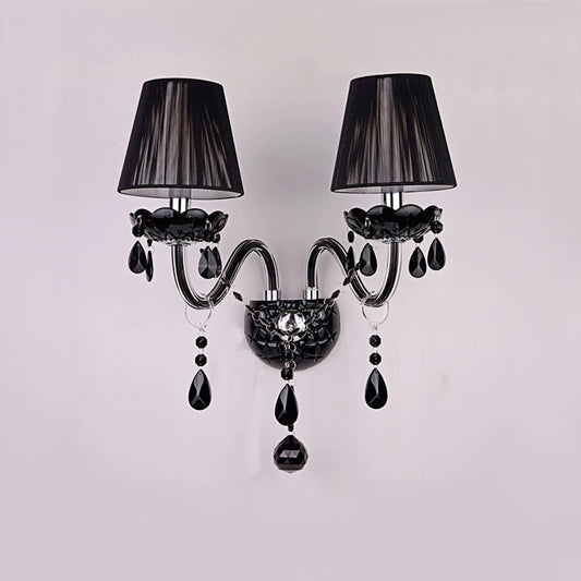 Black wall sconce with two fabric shades and cascading black crystals, mounted on a white wall.