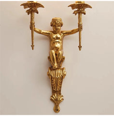 Gold wall sconce with cherub design on a beige background