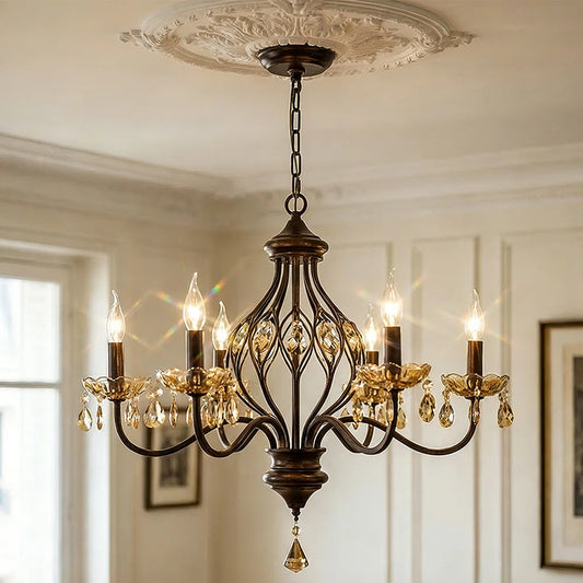Close-up of a bronze-finished chandelier with floral scrollwork and amber crystals hanging from a white ceiling medallion.
