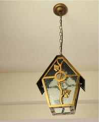 Decorative pendant light with gold accents and glass panels on a neutral background