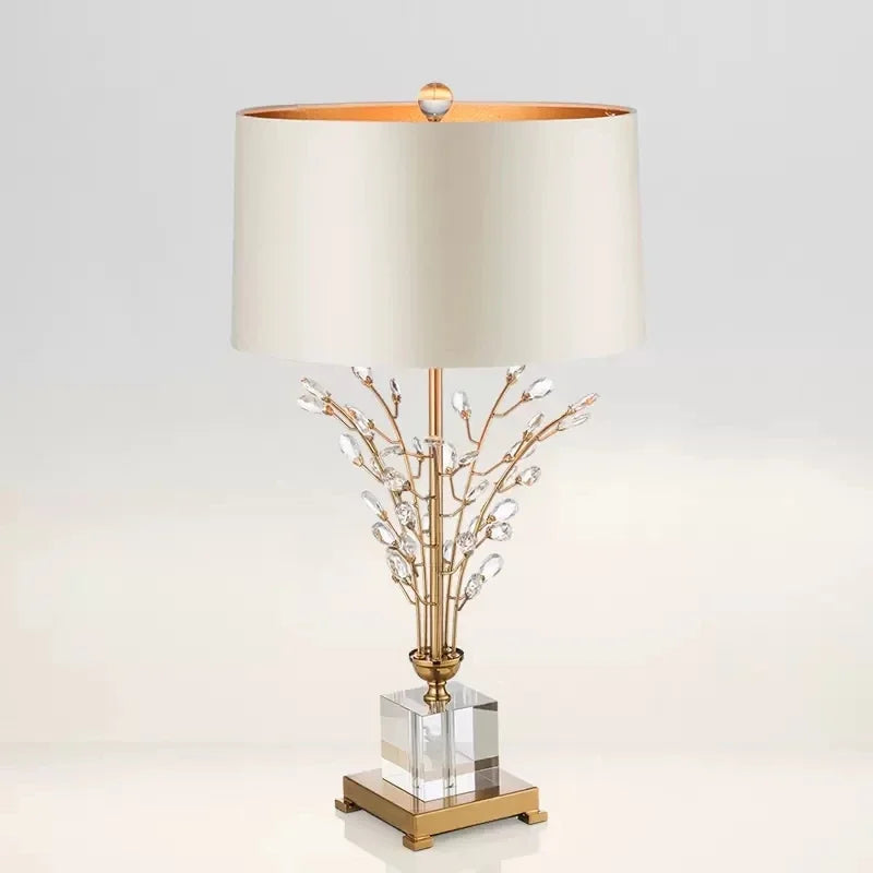 Decorative table lamp with gold base and branch design on a light gray background