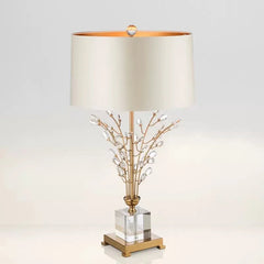 Decorative table lamp with gold base and branch design on a light gray background