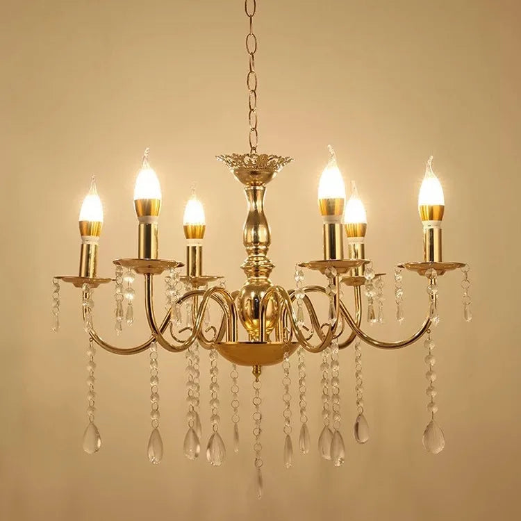 A gold chandelier with six candelabra-style arms, featuring clear teardrop crystals and candle-shaped LED bulbs, shown against a plain background.