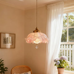 A gold floral pendant light with crystal accents in a room with a window and plants.