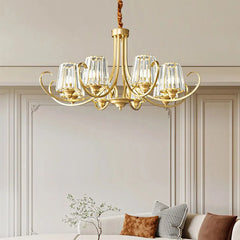 View of a polished gold chandelier with intricate floral details and crystal embellishments over a plush sofa.