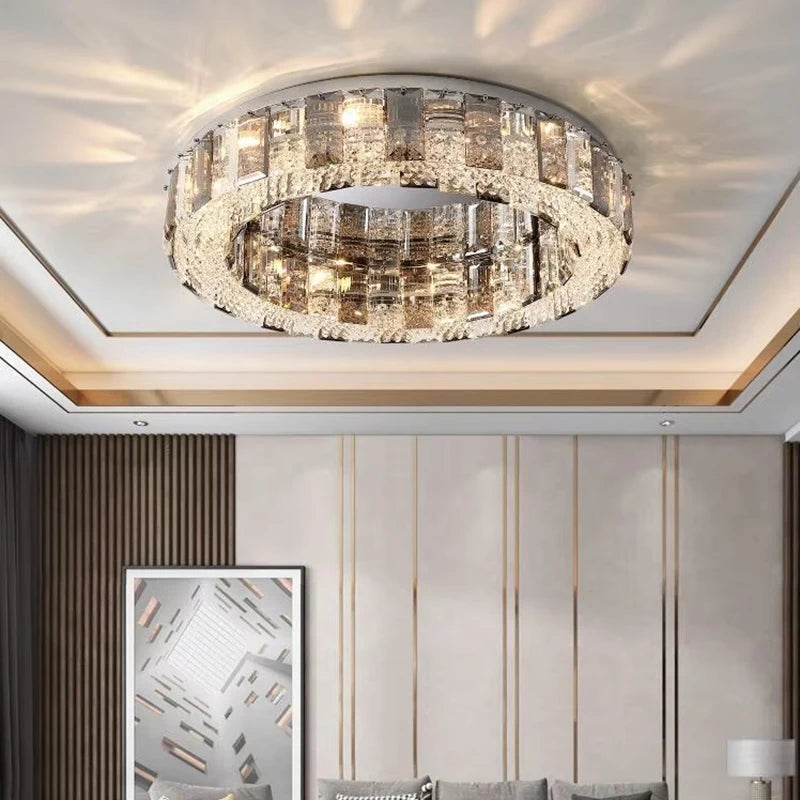 A bedroom with a modern interior, illuminated by a circular semi-flush ceiling light with a chrome frame and crystal embellishments.