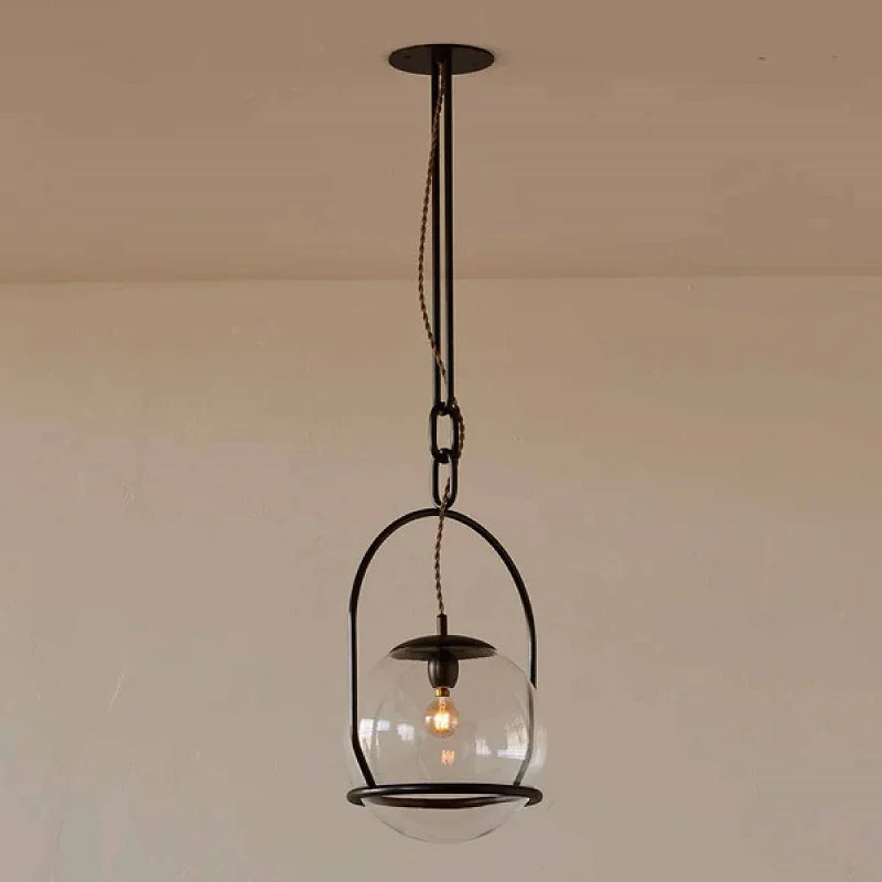 Close-up of the gold metal frame and clear glass globe of a pendant light, showing the E27 socket inside.