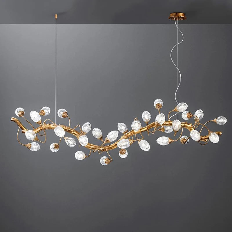 A close-up, isolated view of a gold branch-style chandelier with clear crystal fruit-shaped lights against a dark gray background.