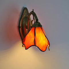 Decorative wall light with orange stained glass shade on a plain background