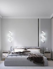 Modern bedroom with a gray bed and decorative pillows, featuring wall lights.