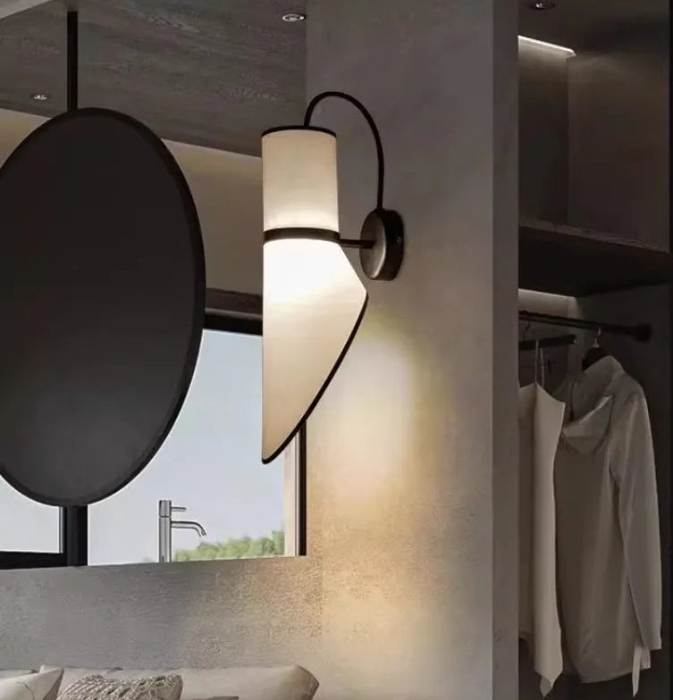 Wall-mounted lamp in a modern interior setting with a window and clothing rack.