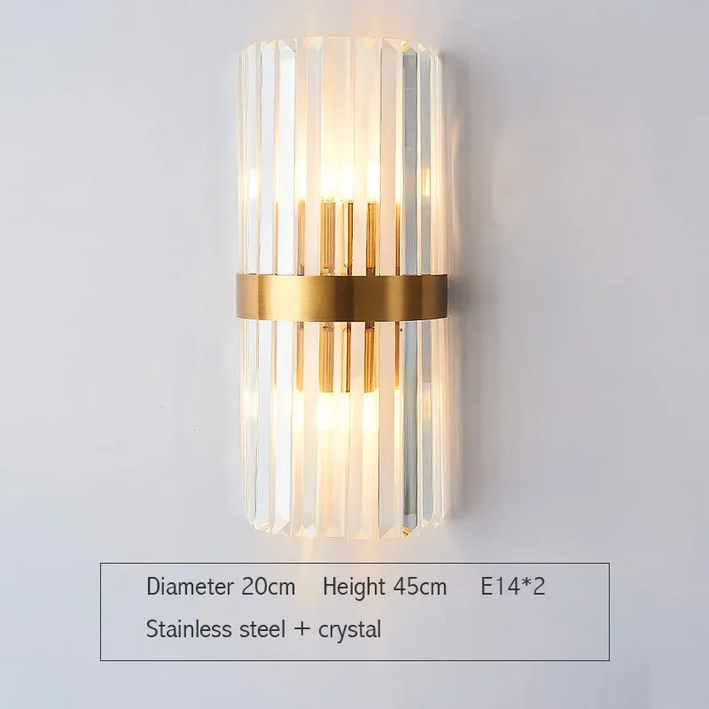 Wall-mounted light fixture with gold band and clear cylindrical design on a white background