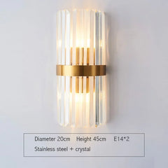 Wall-mounted light fixture with gold band and clear cylindrical design on a white background