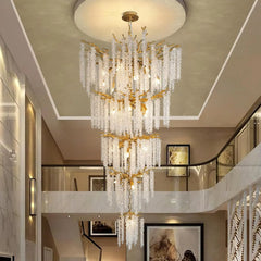 Luxurious chandelier hanging in a stylish interior setting with staircase and wall art.