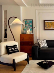 Living room with a black sofa, white armchair, and decorative pillows.