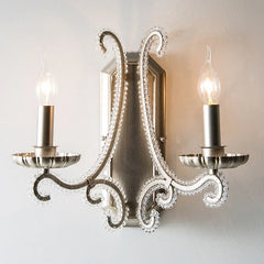 Decorative wall sconce with two candle-style lights on a plain background
