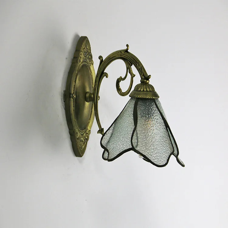 Decorative wall light fixture with glass shade on a white background