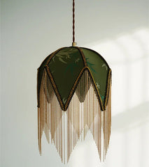 Decorative pendant light with green lampshade and gold fringes on a white background