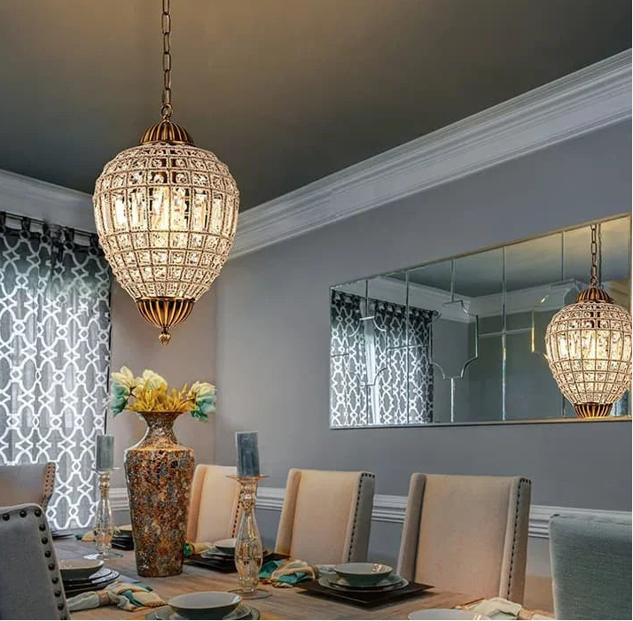 Dining room with a decorative chandelier, table setting, and mirror.