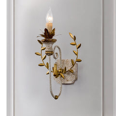 Close-up of a distressed gold floral leaf wall sconce showing intricate detailing and a candle-style light.