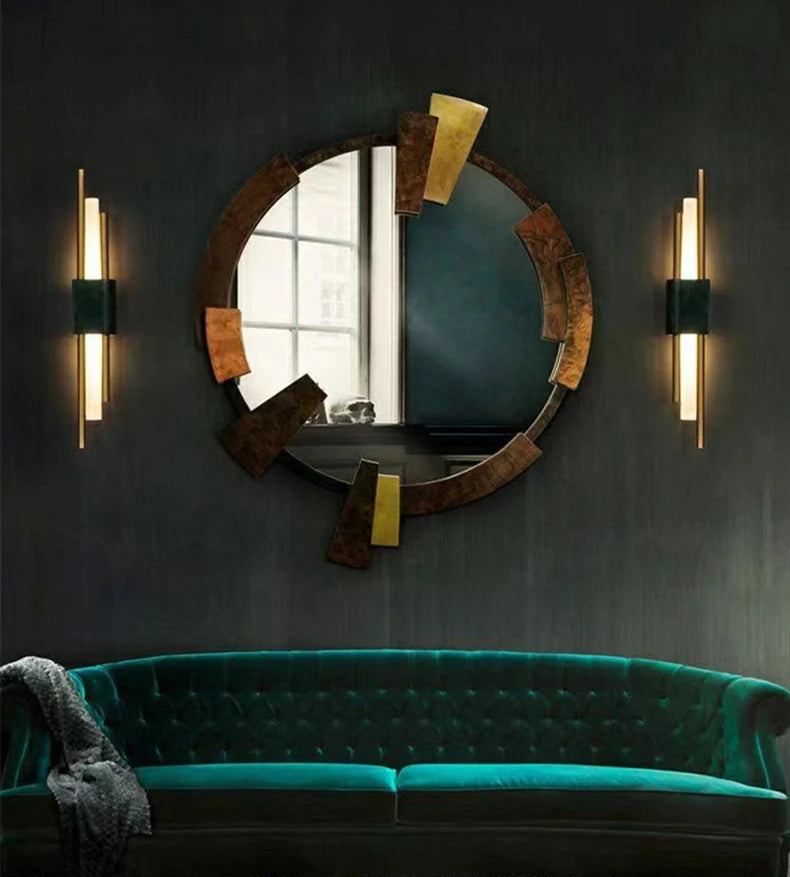 Decorative mirror with gold accents above a green sofa in a room with dark walls.