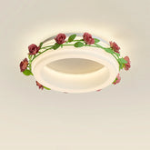 Close-up of a white semi-flush ceiling light featuring a ring design wrapped with a green vine and pink roses.