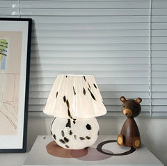 Table lamp with spotted design and wooden bear figurine.