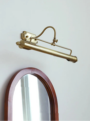 Brass wall-mounted lamp with a mirror on a light gray background