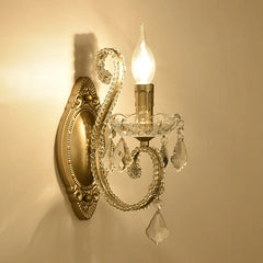 Decorative wall sconce with crystal accents and a lit bulb on a beige wall.