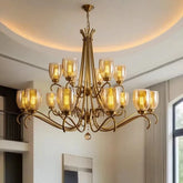 A grand gold tiered chandelier with floral-inspired arms and seeded glass shades, hanging from a white ceiling.