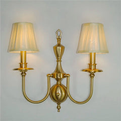 Gold wall sconce with two lampshades on a plain background